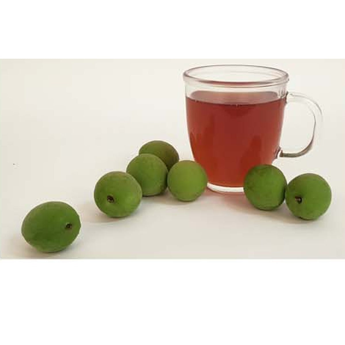 Diluted maesil plum tea in a glass mug with fresh green plums