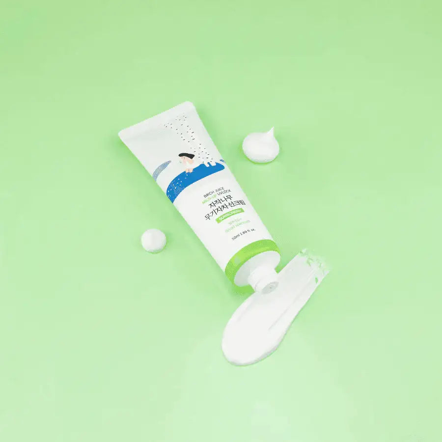 Round Lab Birch Juice Mild Up sunscreen tube on green background